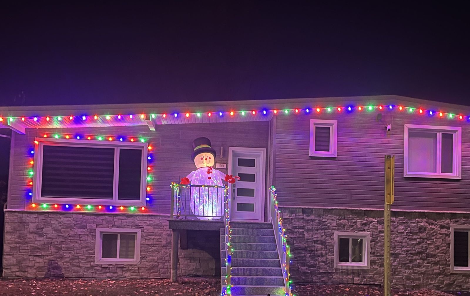 Maison décorée de lumières colorées et d'un bonhomme de neige gonflable