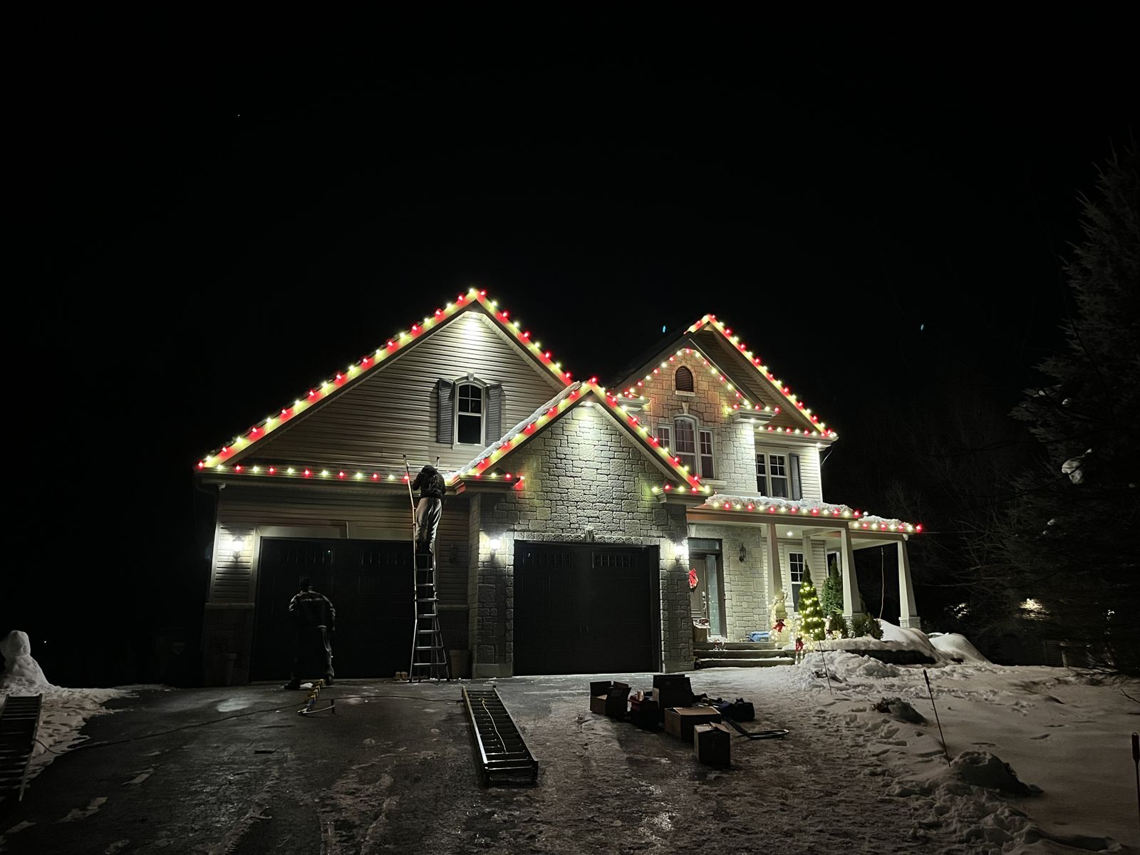 Notre équipe installant des lumières de Noël sur une échelle