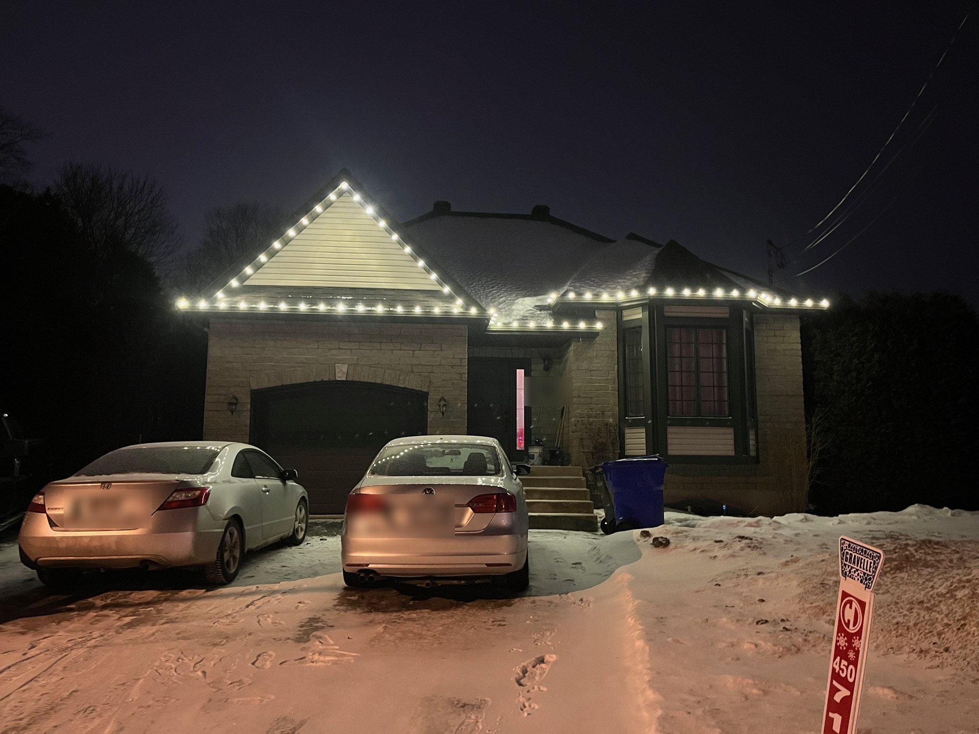 Maison illuminée de lumières de Noël blanches le long du toit, dans la neige
